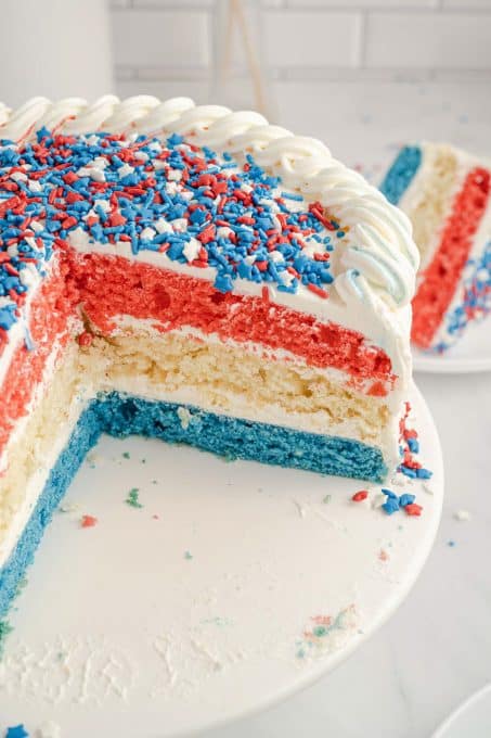 A cake with red, white, and blue layers and white frosting with sprinkles.