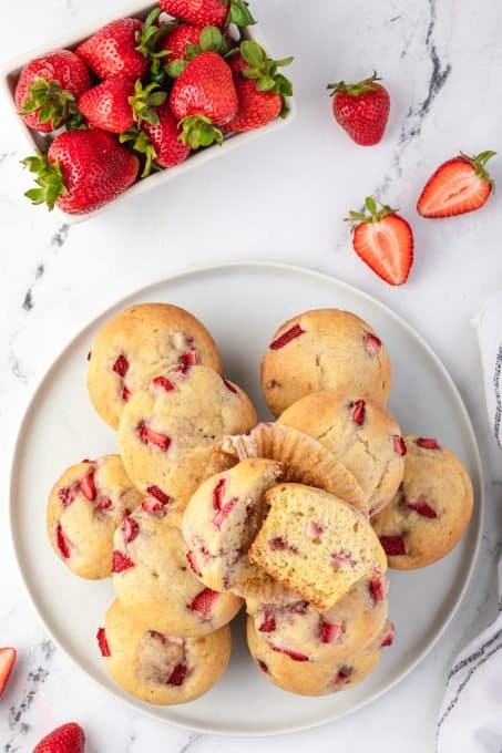 A plate of muffins with fresh strawberries.
