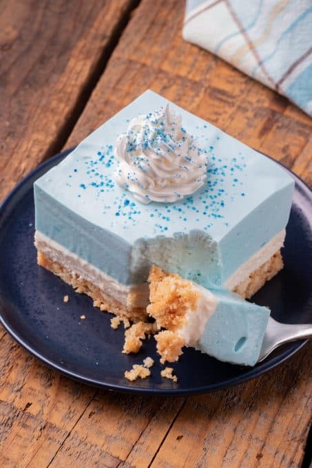 A bite taken out of a no bake layered blue dessert.