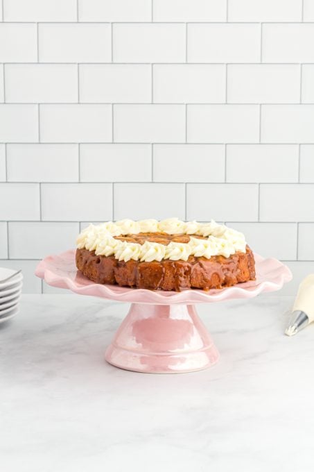 A cinnamon cake with icing on a cake plate.