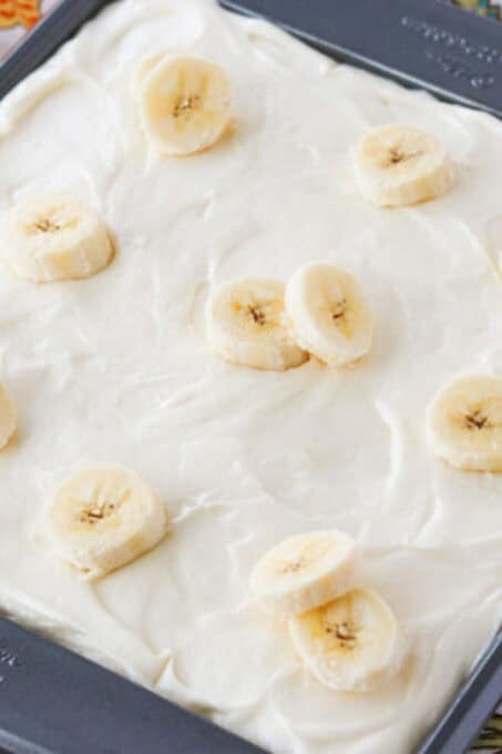 The top of a cream cheese covered cake with sliced bananas.