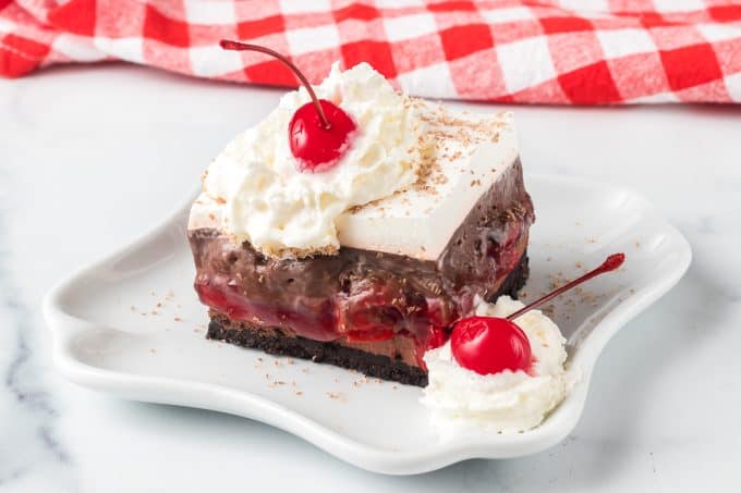 Dream Bars with a cookie crust, chocolate cheesecake, chocolate pudding, and whipped topping.