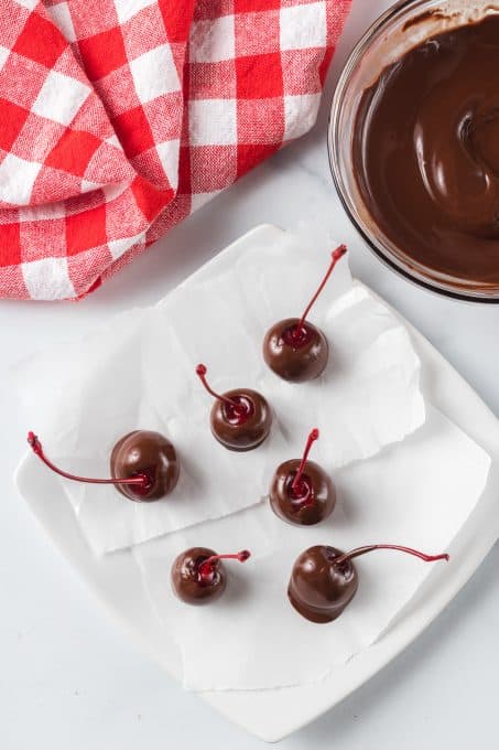Some chocolate dipped cherries setting on parchment.