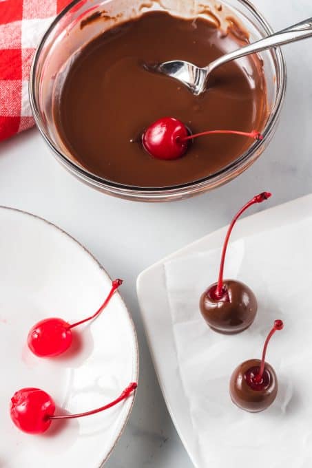 Dipping cherries in melted chocolate.