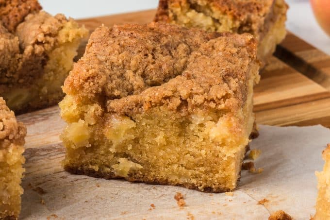 A slice of cake filled with apples, and topped with a cinnamon streusel.