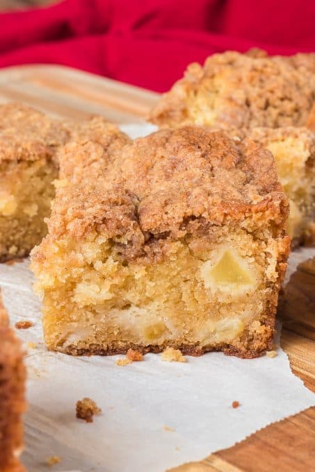 A slice of a buttery cake filled with apples and a cinnamon crumb topping.
