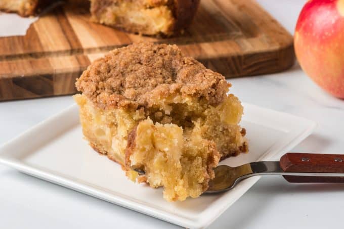 A bite taken out of an apple cake with cinnamon topping.