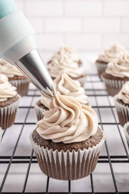 Piping Oreo frosting onto a chocolate cupcake.
