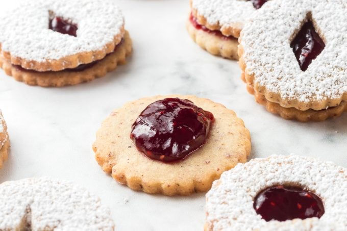 Spreading jam on the bottom of a sandwich cookie.