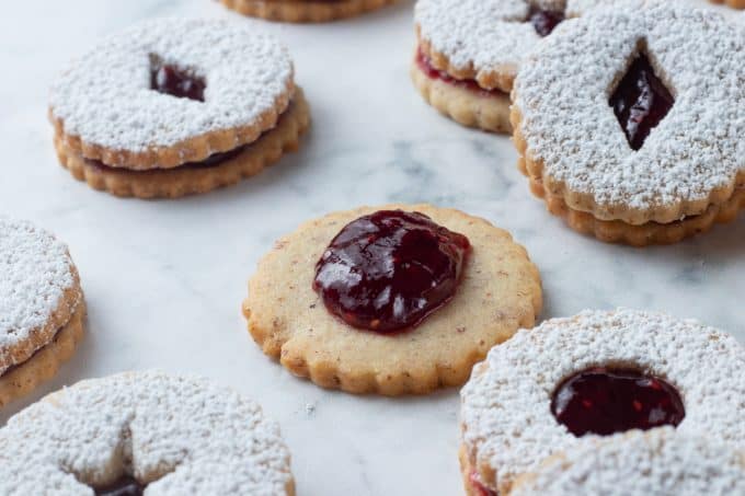 Spreading jam on the bottom of a sandwich cookie.