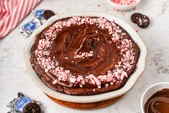 A brownie pie decorated with chocolate ganache and peppermint candies.