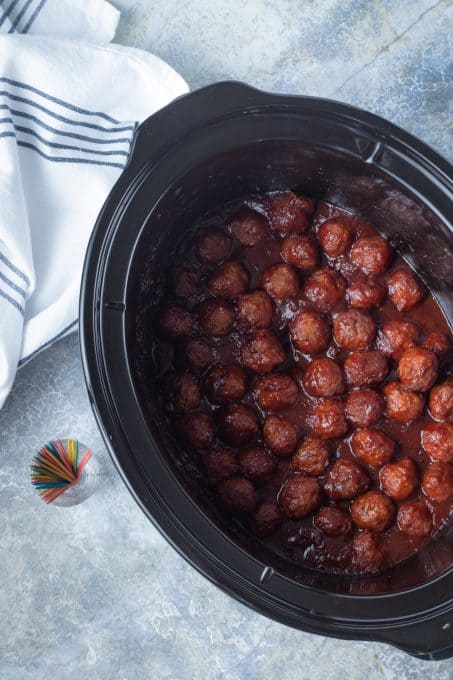 A slow cooker with mini meatballs and other ingredients.