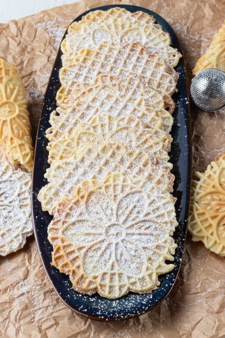 Italian cookies dusted with sugar on a serving platter.