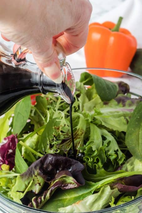 Pouring a balsamic reductio over a salad.