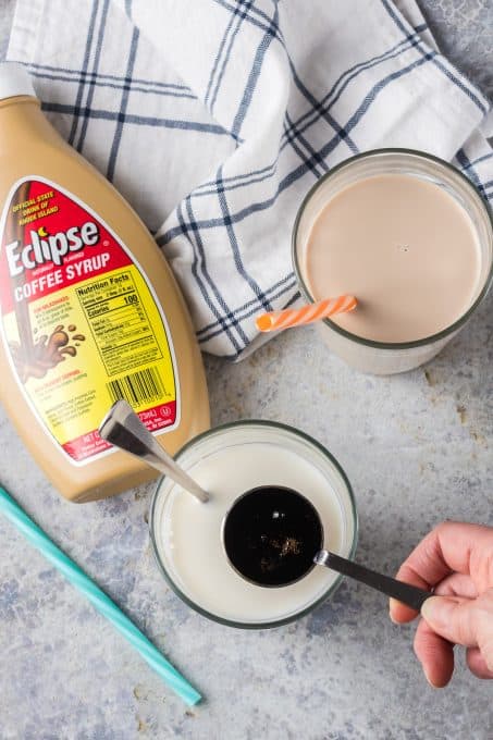 Pouring Eclipse coffee syrup into a glass of milk.