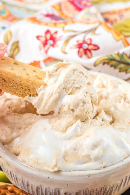 Dipping a shortbread cookie into a peanut butter dip.