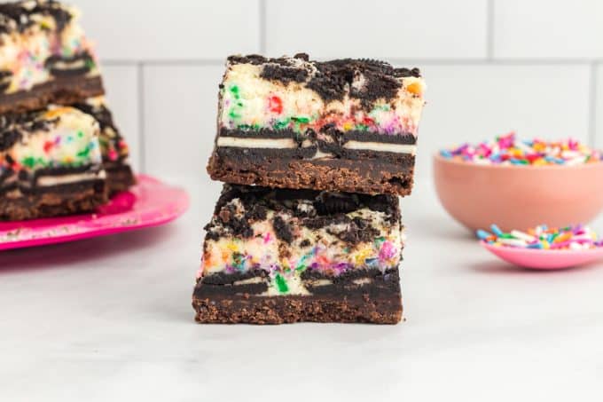 Stacked Funfetti Bars with cheesecake and Oreos.
