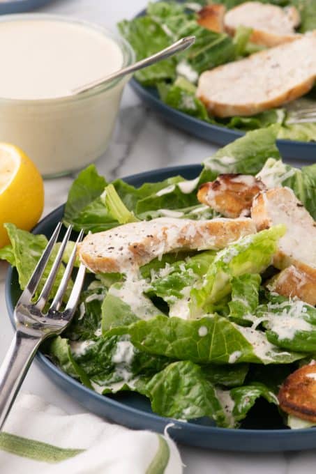 A salad with chicken and Caesar dressing.