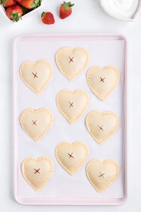 Heart shaped hand pies with strawberry filling ready for the oven.