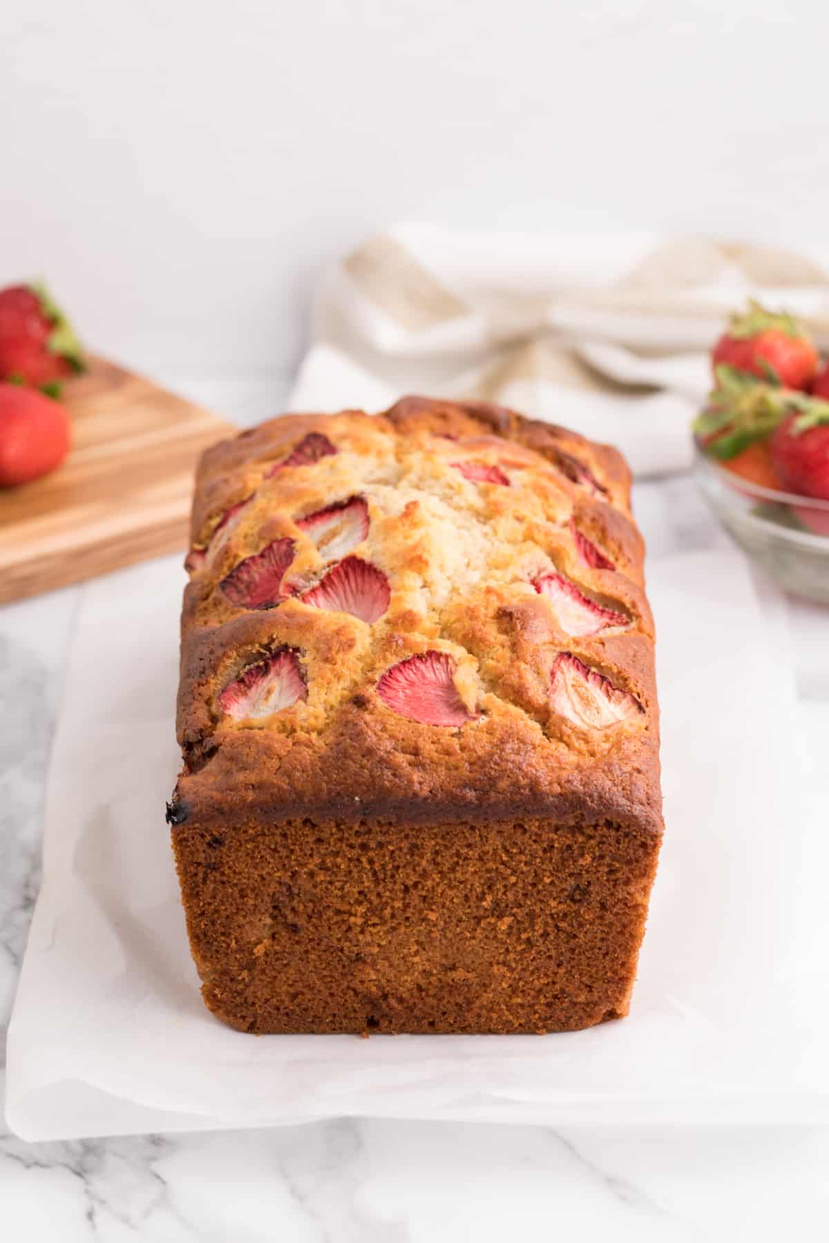 A loaf of banana bread with sliced strawberries baked in.