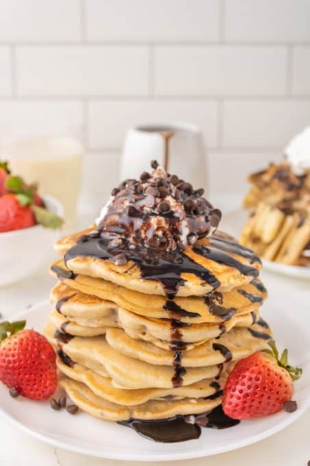 Pancakes with chocolate chips topped with whipped cream and chocolate syrup.