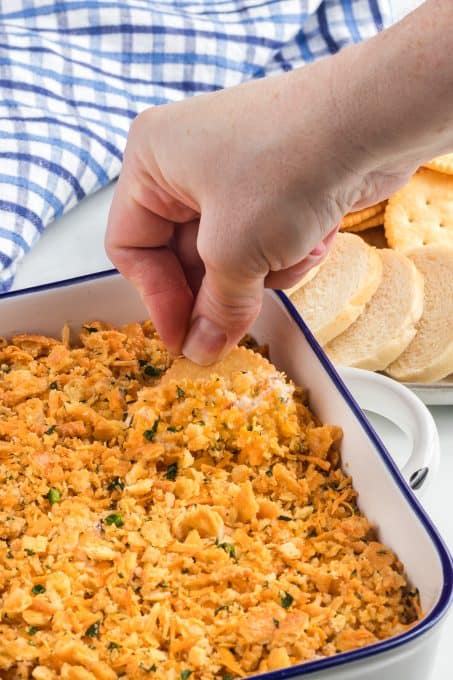 Dipping a cracker into a dip with cheese, sour cream and jalapenos.