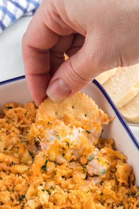Scooping jalapeno cheese dip onto a cracker.