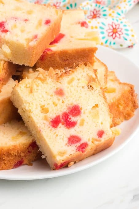 Slices of a coconut quick bread with cherries and pineapple.