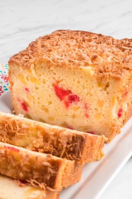 A loaf of quick bread with cherries, pineapple and coconut.