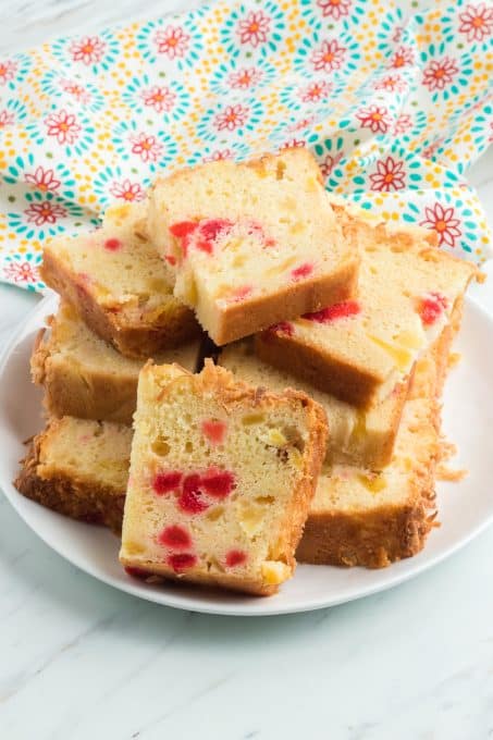 A plate of pineapple bread slices with cherries and coconut.