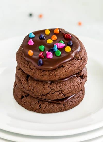 A stack of Brownie Cookies with chocolate frosting and cosmic sprinkles.