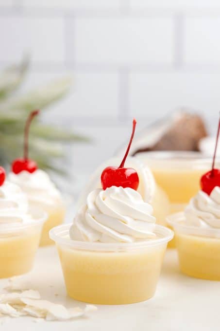 Whipped Cream and a Maraschino cherry on top of a jello shot.