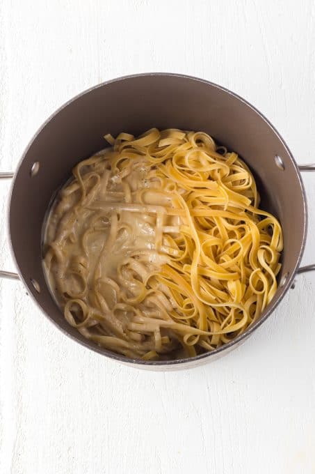 Pasta and an Alfredo sauce tossed together in a pot.