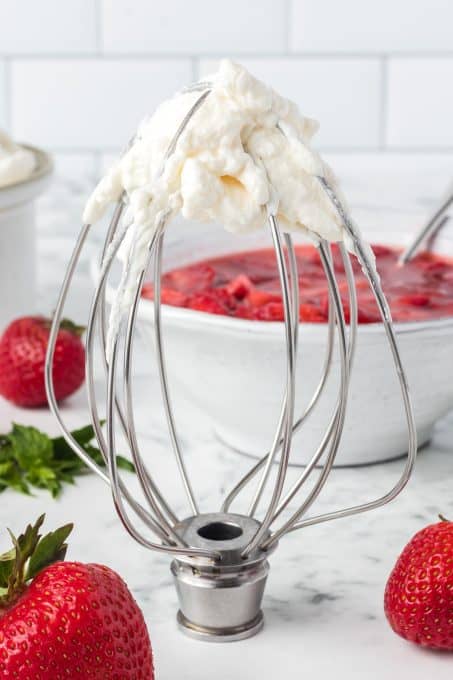 A whisk attachment with cream that's been whipped.