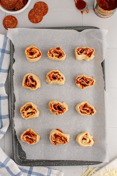 Pinwheels with pepperoni and pizza sauce ready to be baked.