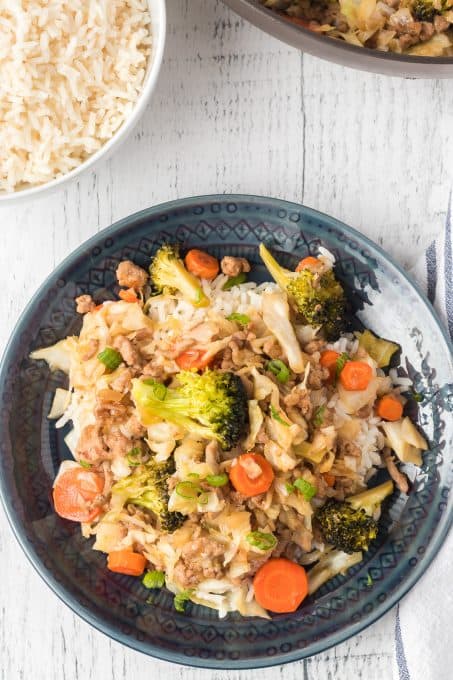 A plate of stir fried pork and cabbage, carrots and broccoli.