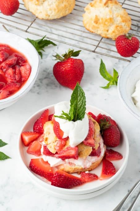 A plate of strawberries, whipped cream, and homemade biscuits.