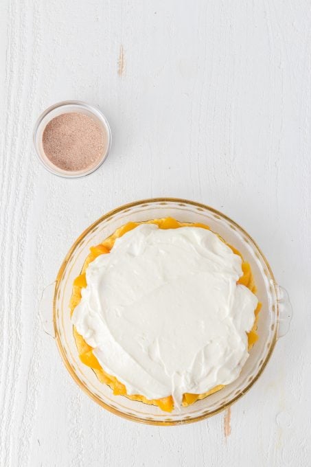 Spreading the sweetened cream cheese over the peaches for an easy dessert.