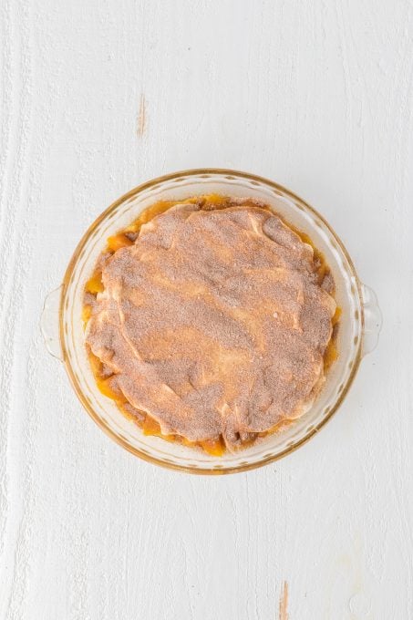 Cinnamon sugar on top of a peach pie.