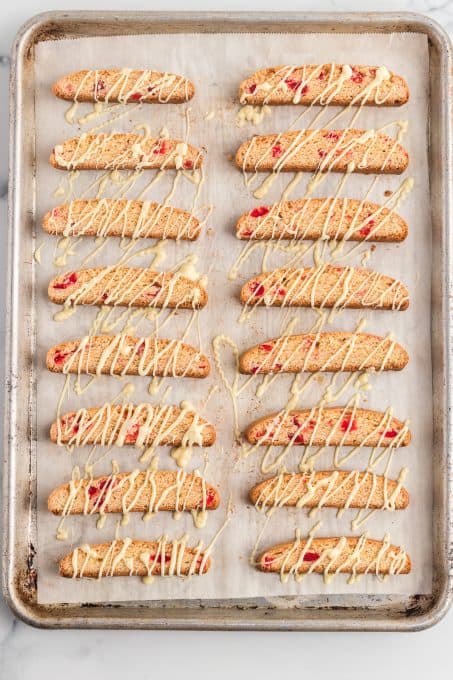 Drizzled white chocolate over biscotti with cherries.