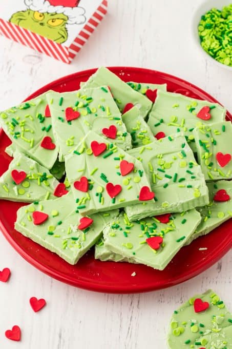 A plate full of white chocolate bark that is Grinch themed.