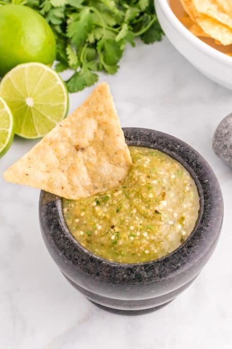 Tortilla chip dipping in a tomatillo salsa.