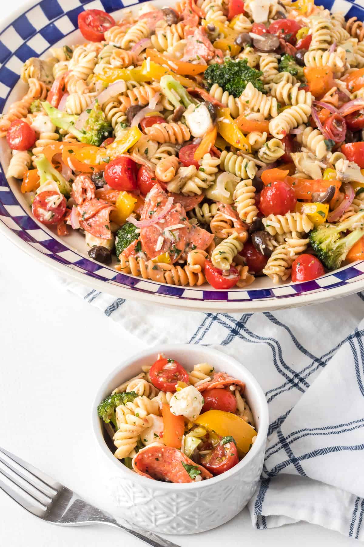 Bowls of pasta salad with olives, cheese, pepperoni, peppers tossed in an Italian dressing.