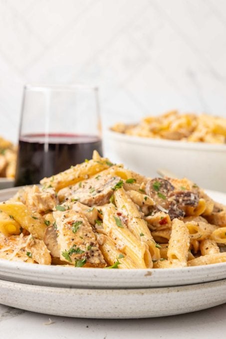 A plate full of chicken pasta with mushrooms and cheese.