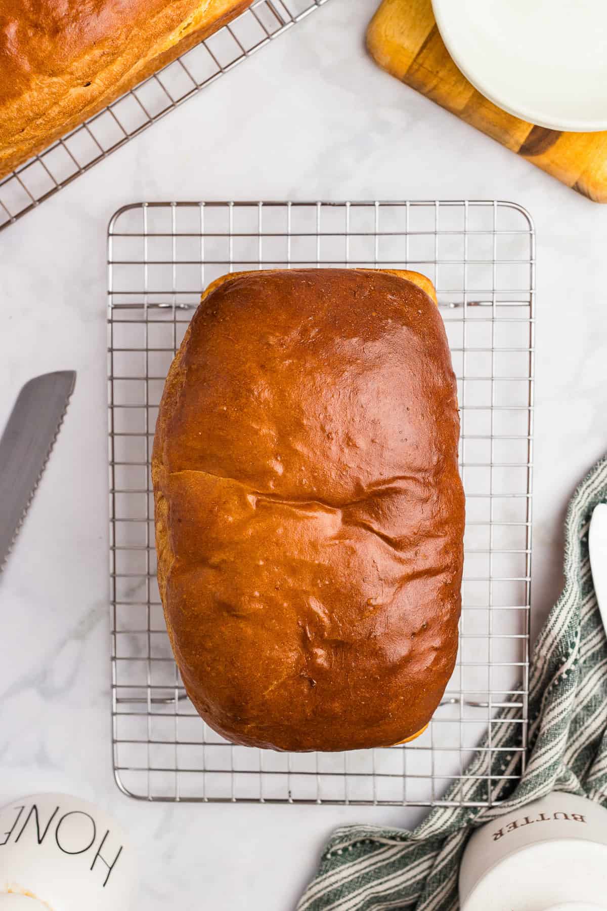 An egg washed loaf of bread cooling on a wire rack.