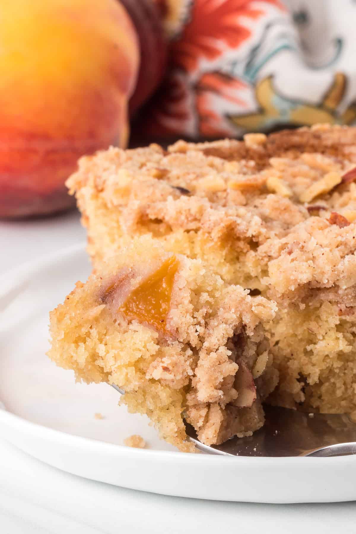 A bite taken out of a peach cake dessert.