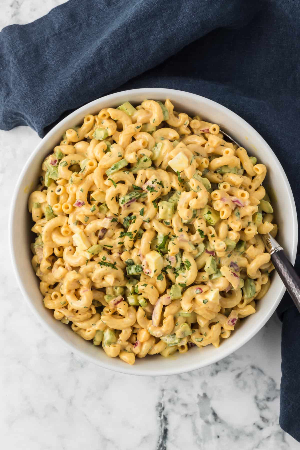 A serving bowl full of a salad with macaroni.