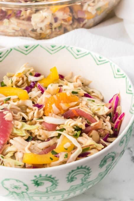 A bowl of an Asian inspired chicken salad with dry ramen noodles.