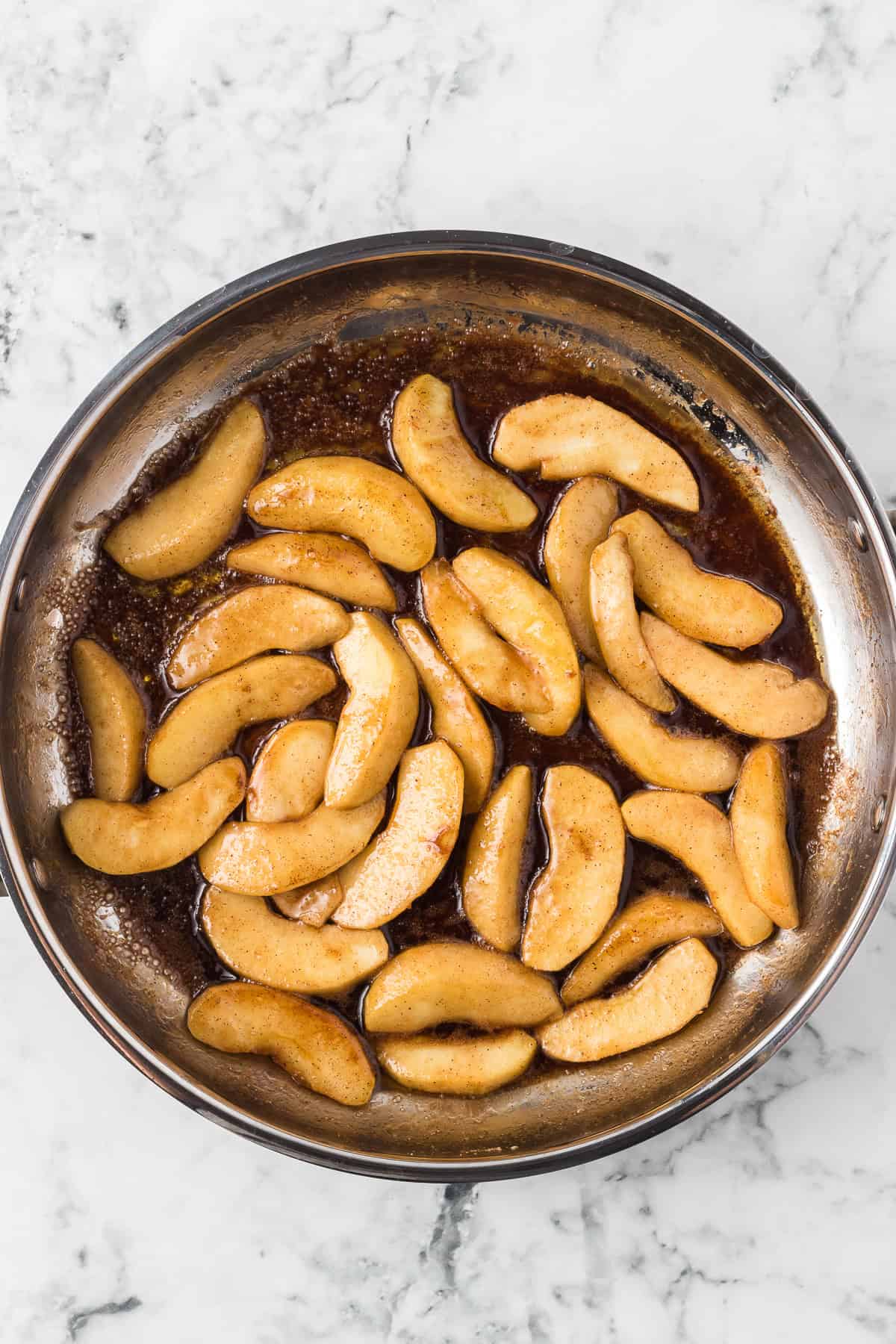 Apple slices being fried in a cinnamon spice butter mixture.