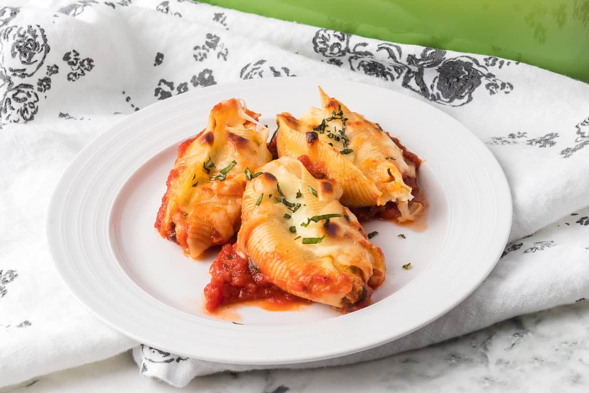 Three Stuffed Shells with Ricotta on a plate with a gray floral napkin.